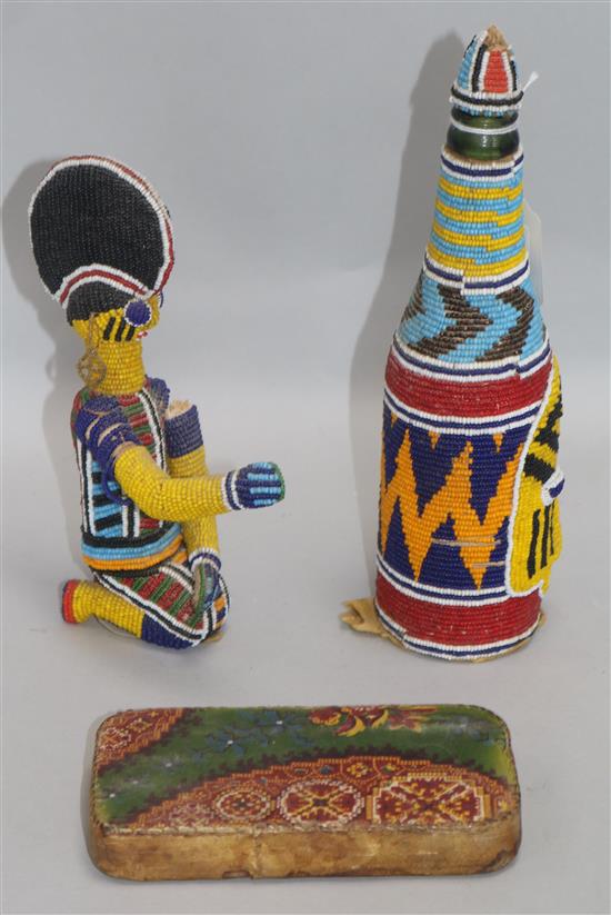 A Nigerian beadwork-covered glass bottle, with mask and geometric decoration and a similar kneeling figure